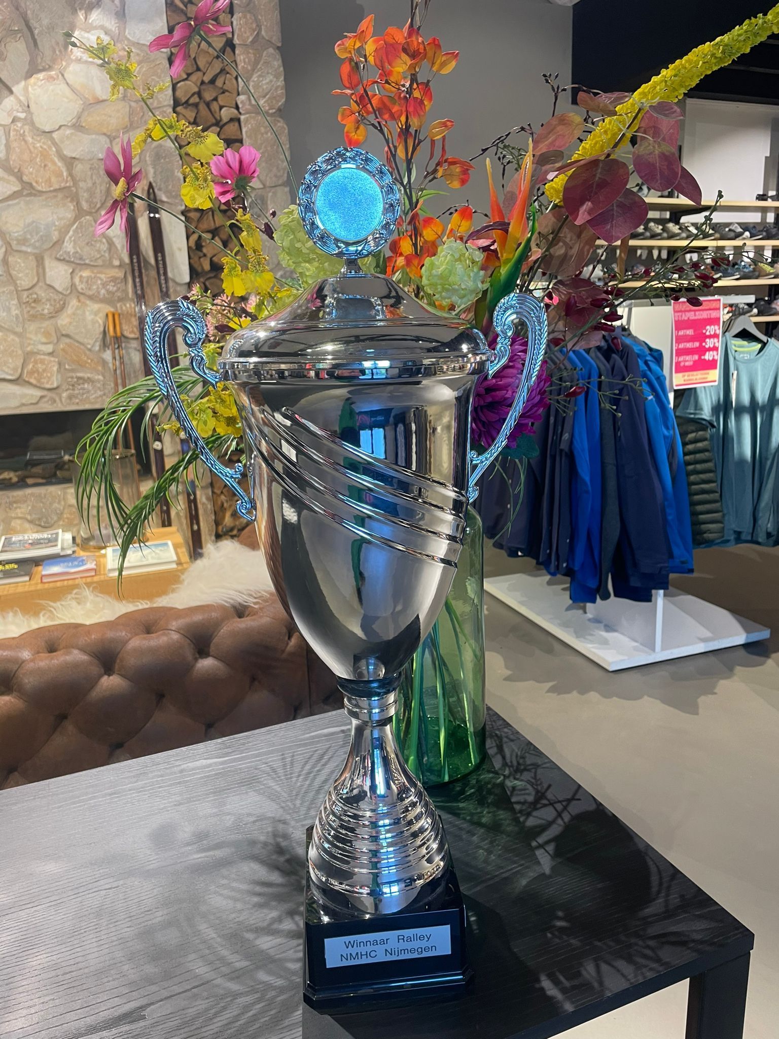 Zilveren trofee met kleurrijke bloemen in een winkelomgeving.