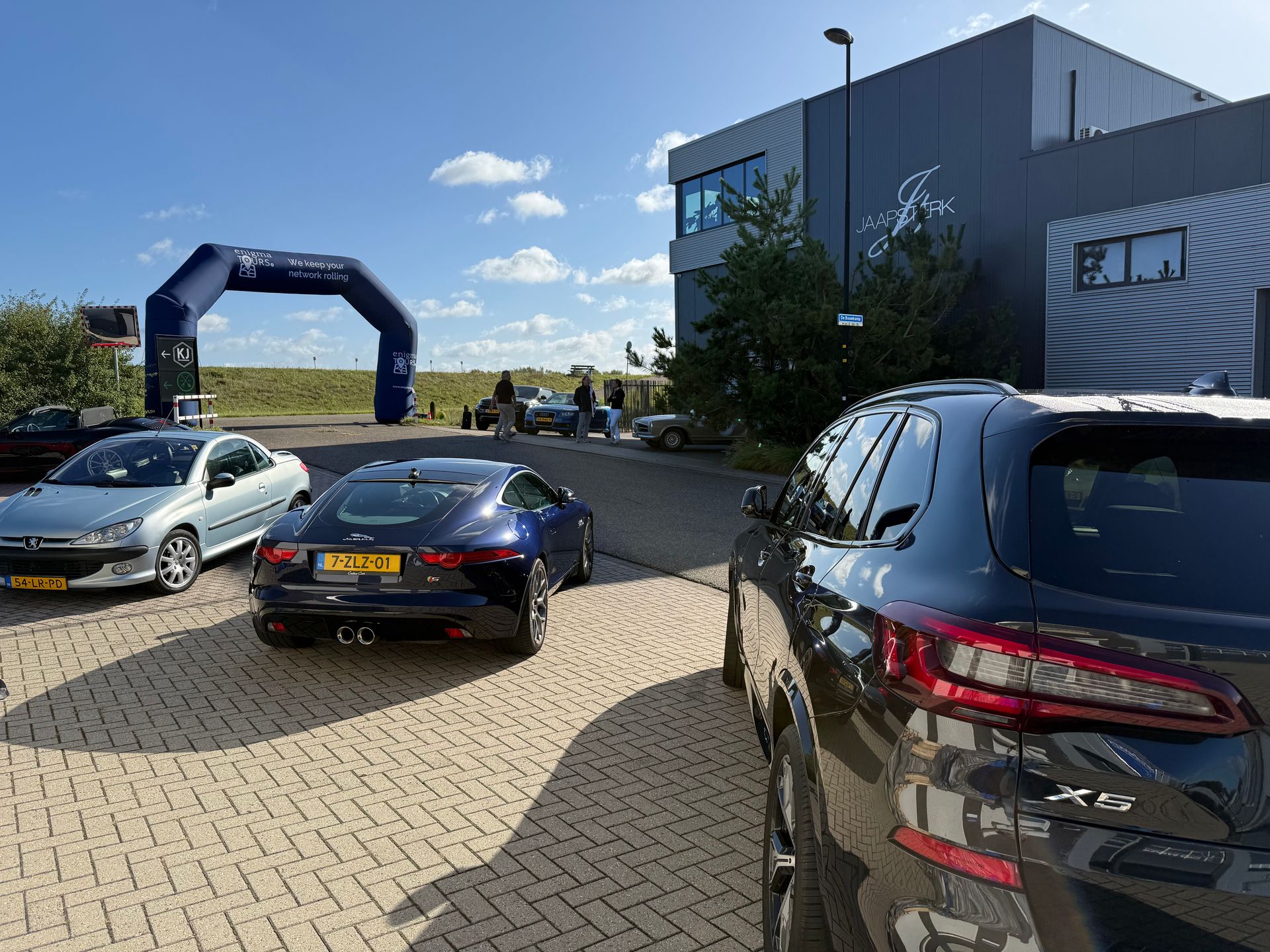 Auto's geparkeerd bij een evenement voor een gebouw met een boog.