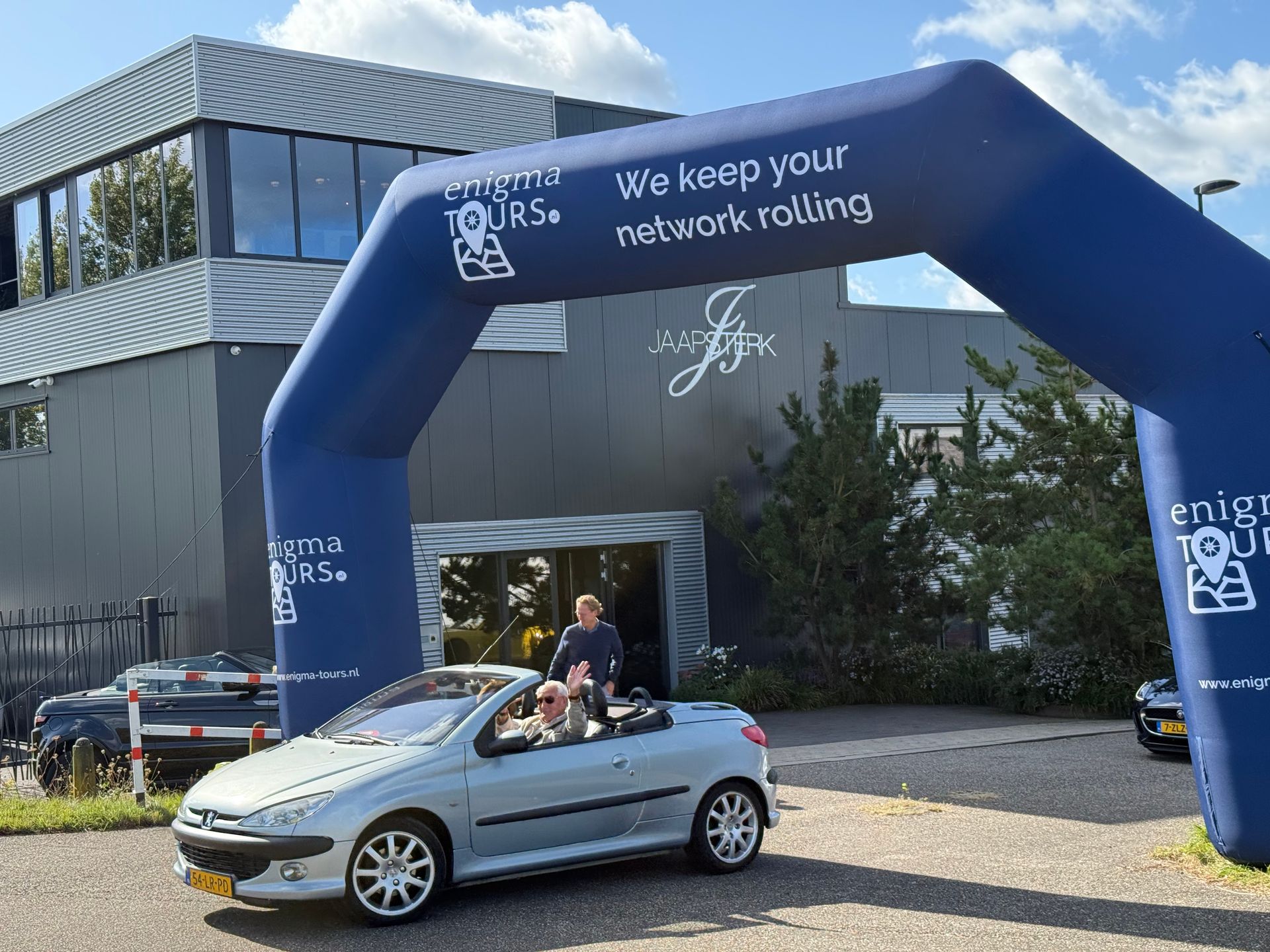 Een cabriolet rijdt onder een boog door met de reclame