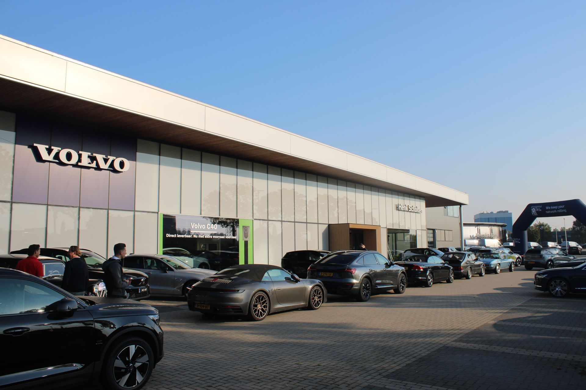 Volvo-dealer met auto's buiten geparkeerd, evenement gaande, zonnige dag.