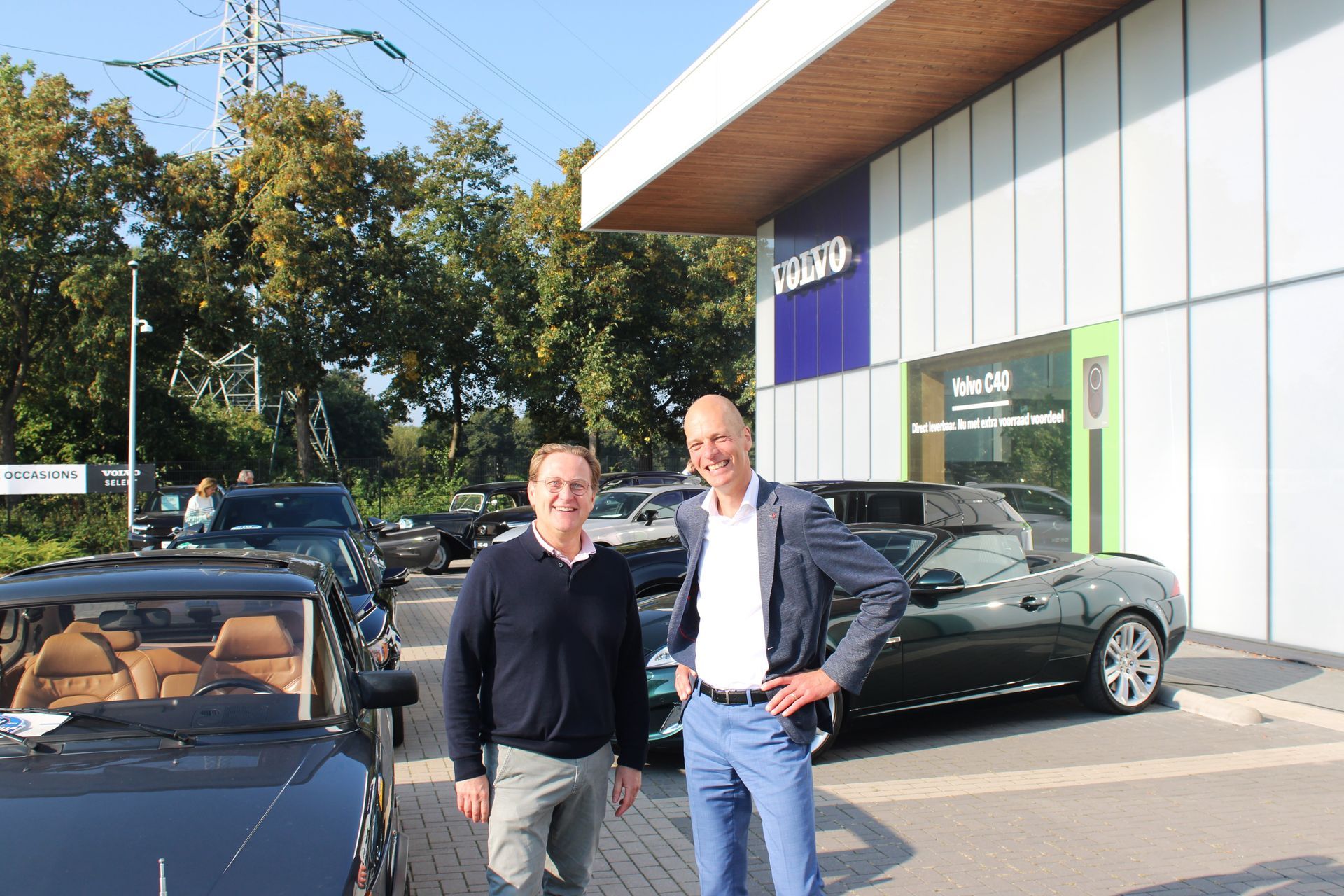 Twee mannen staan ​​bij auto's voor een Volvo-dealer.