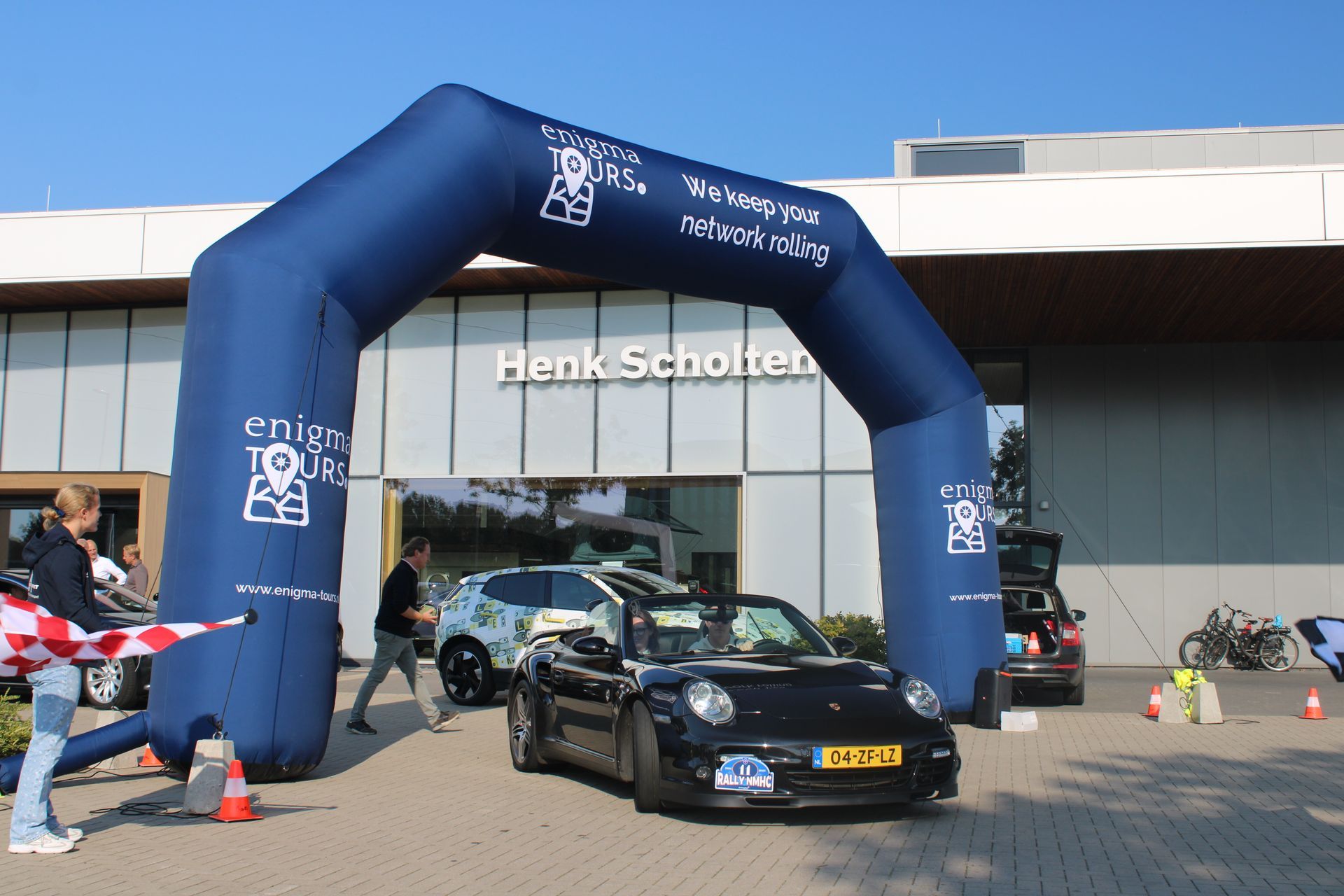 Zwarte Porsche onder een opblaasbare boog; gebouw 