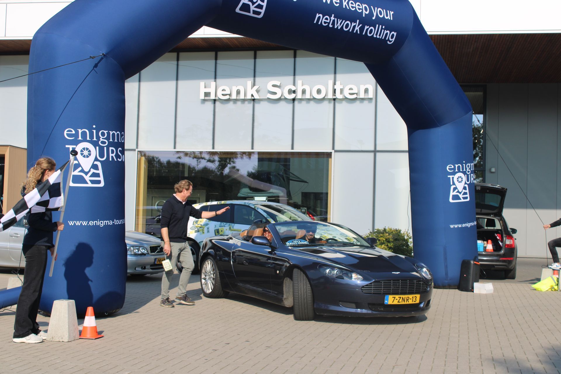 Een auto rijdt onder een opblaasbare boog met het opschrift 