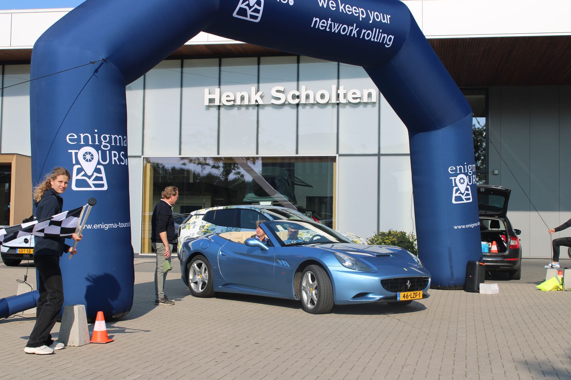 Een blauwe Ferrari staat onder een opblaasbare boog met het opschrift 