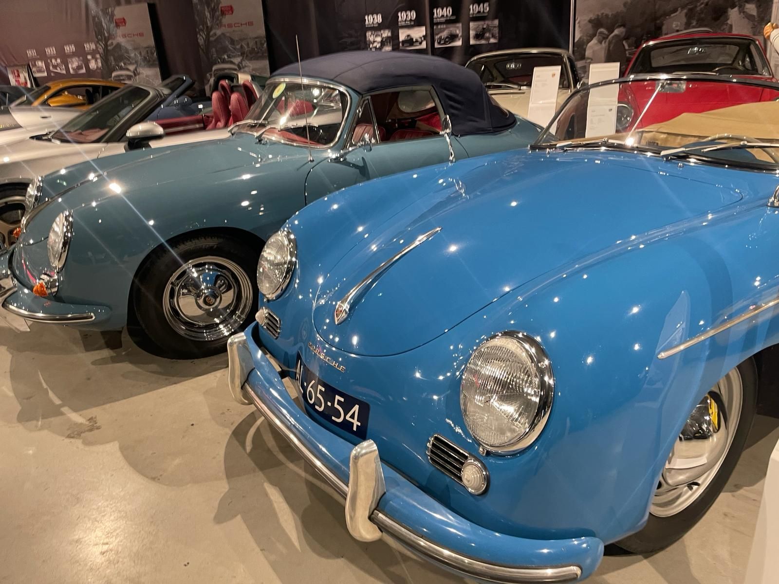 Twee klassieke blauwe Porsche cabriolets tentoongesteld op een autoshow.