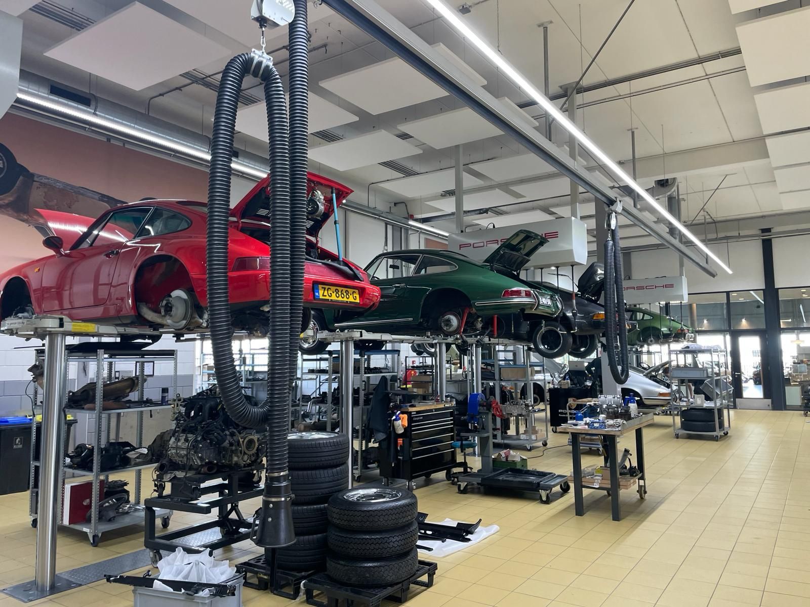 In een lichte, moderne autogarage staan ​​diverse klassieke auto's op hefbruggen.