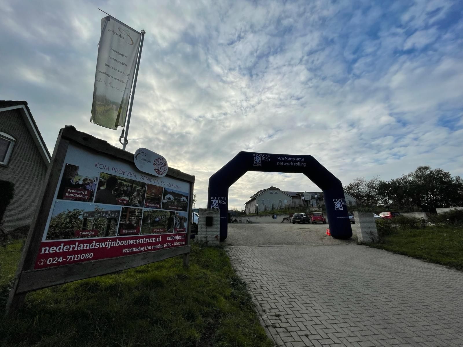 Toegangspoort met evenementborden, bewolkte lucht erboven.