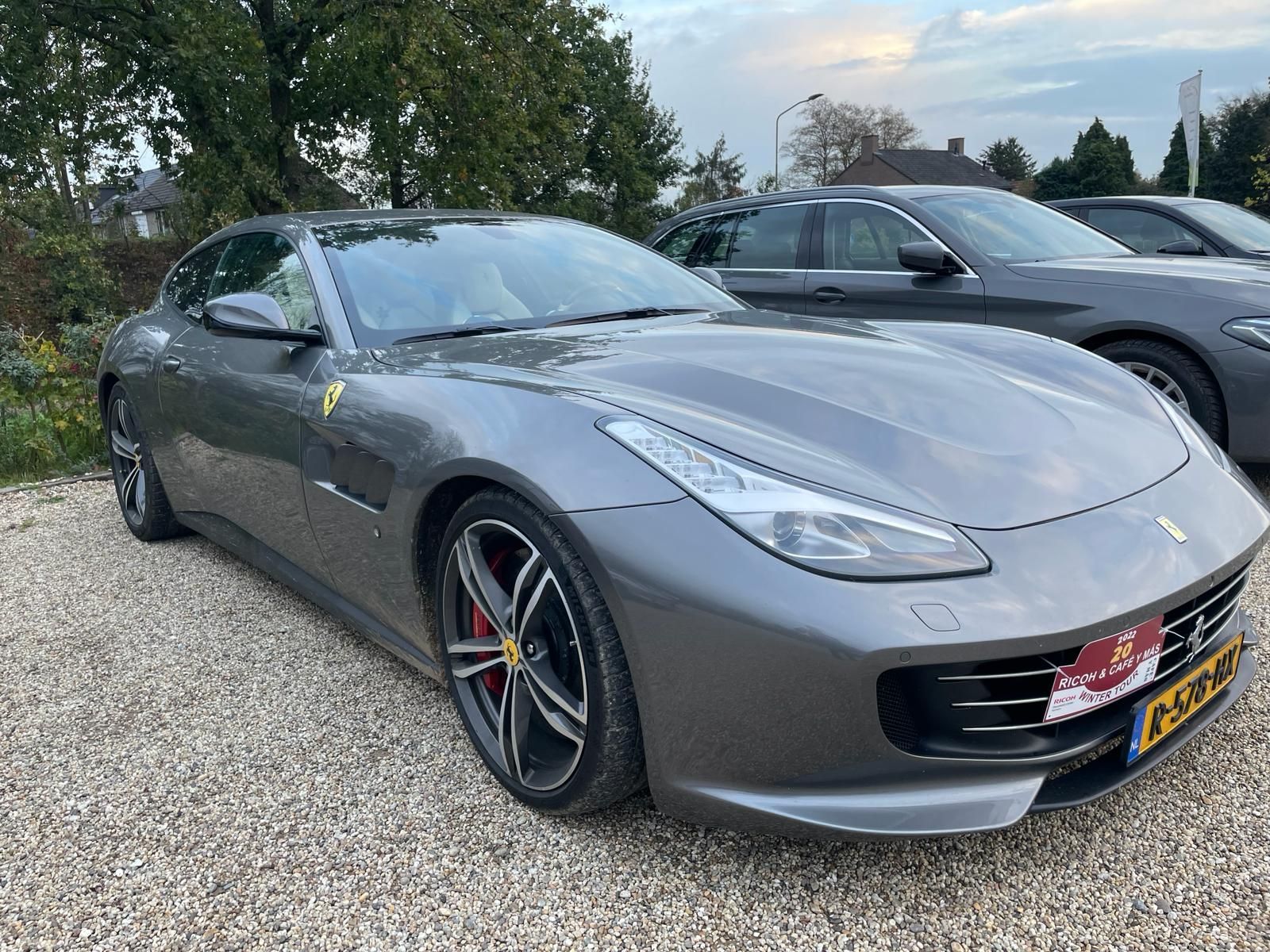 Grijze Ferrari geparkeerd op grind.