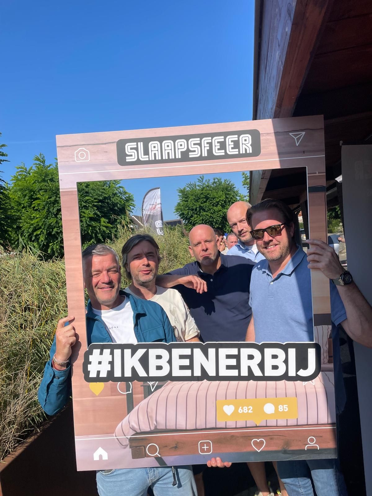Vijf mannen poseren in een grote fotolijst met de opschriften