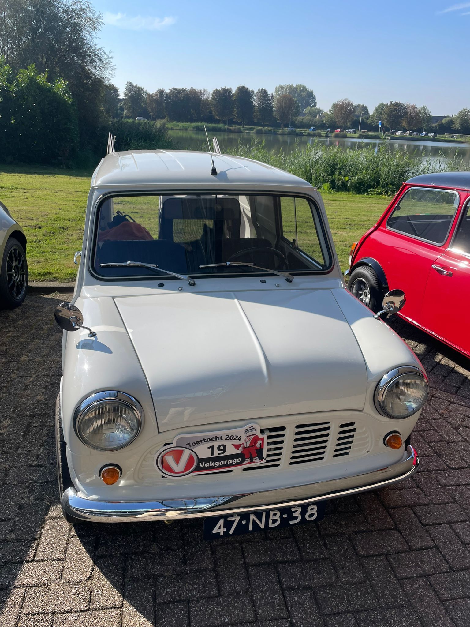 Witte klassieke Mini-bus met chromen details, buiten geparkeerd, vooraanzicht.
