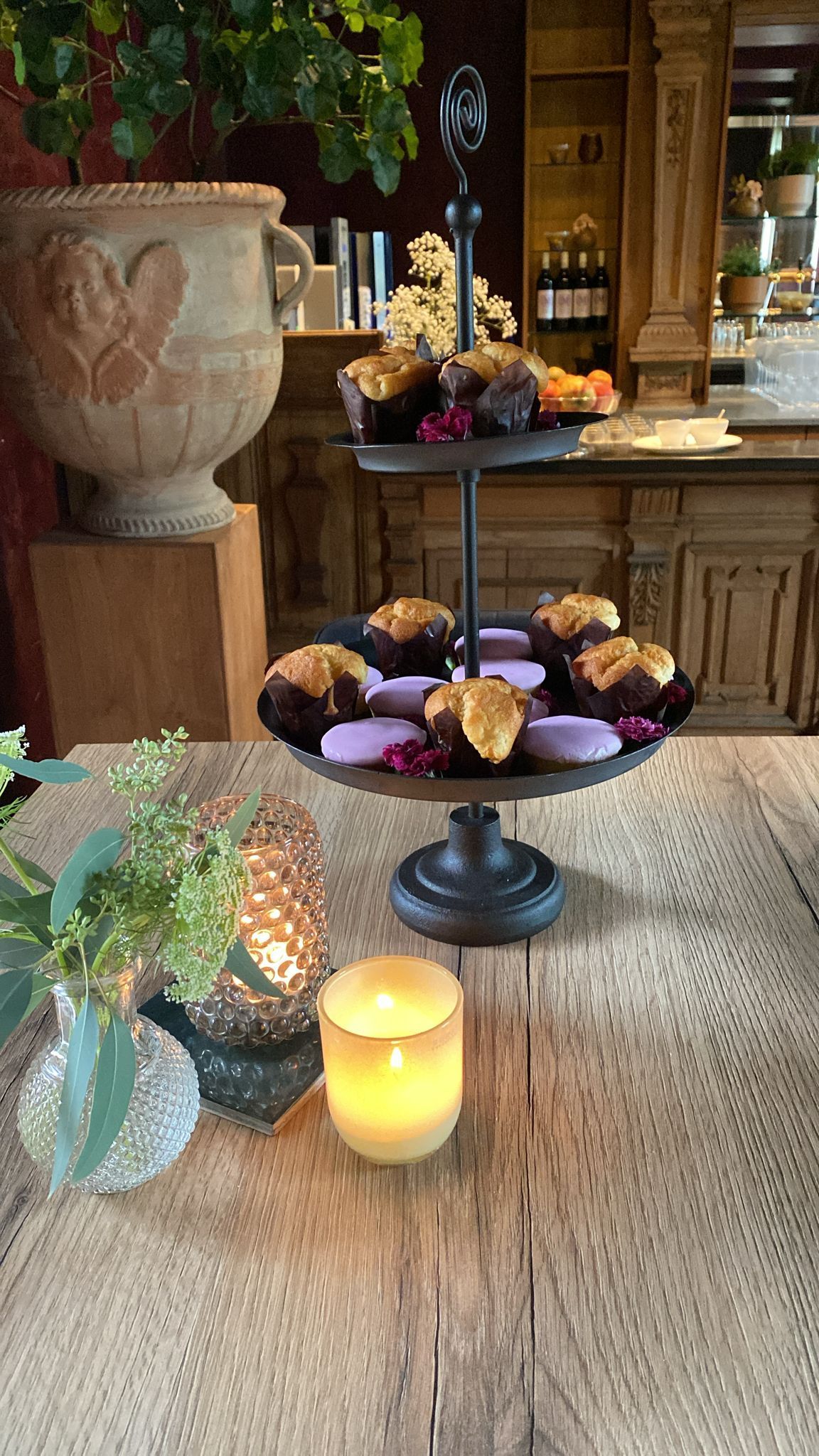 Een etagère met muffins en een kaars op tafel.