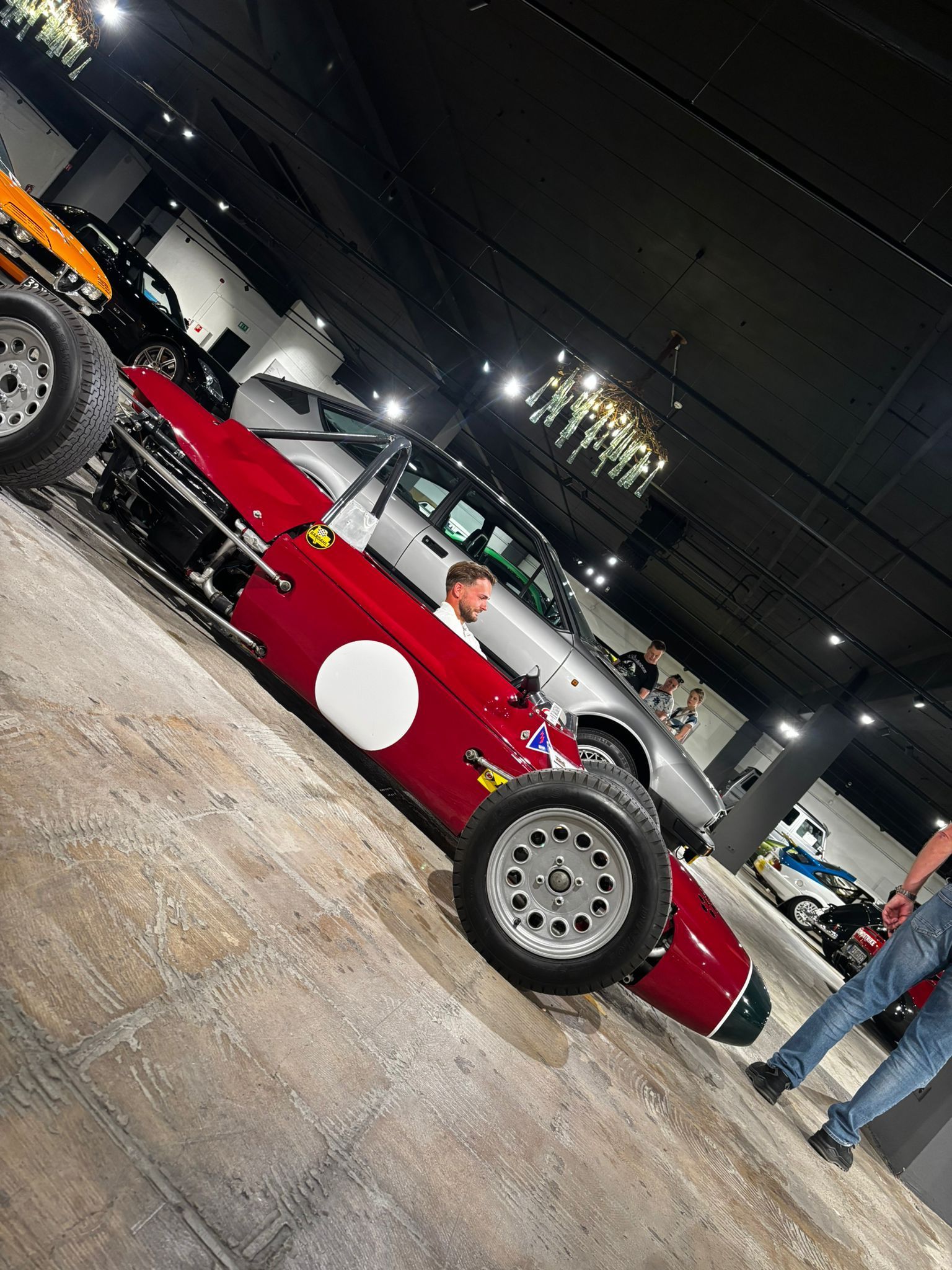 Rode vintage raceauto met witte cirkel, man in de cockpit, in een museum.