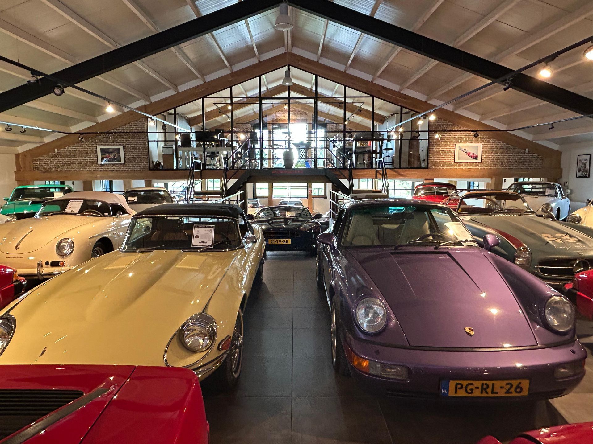Klassieke auto's tentoongesteld in een grote showroom met een tussenverdieping.