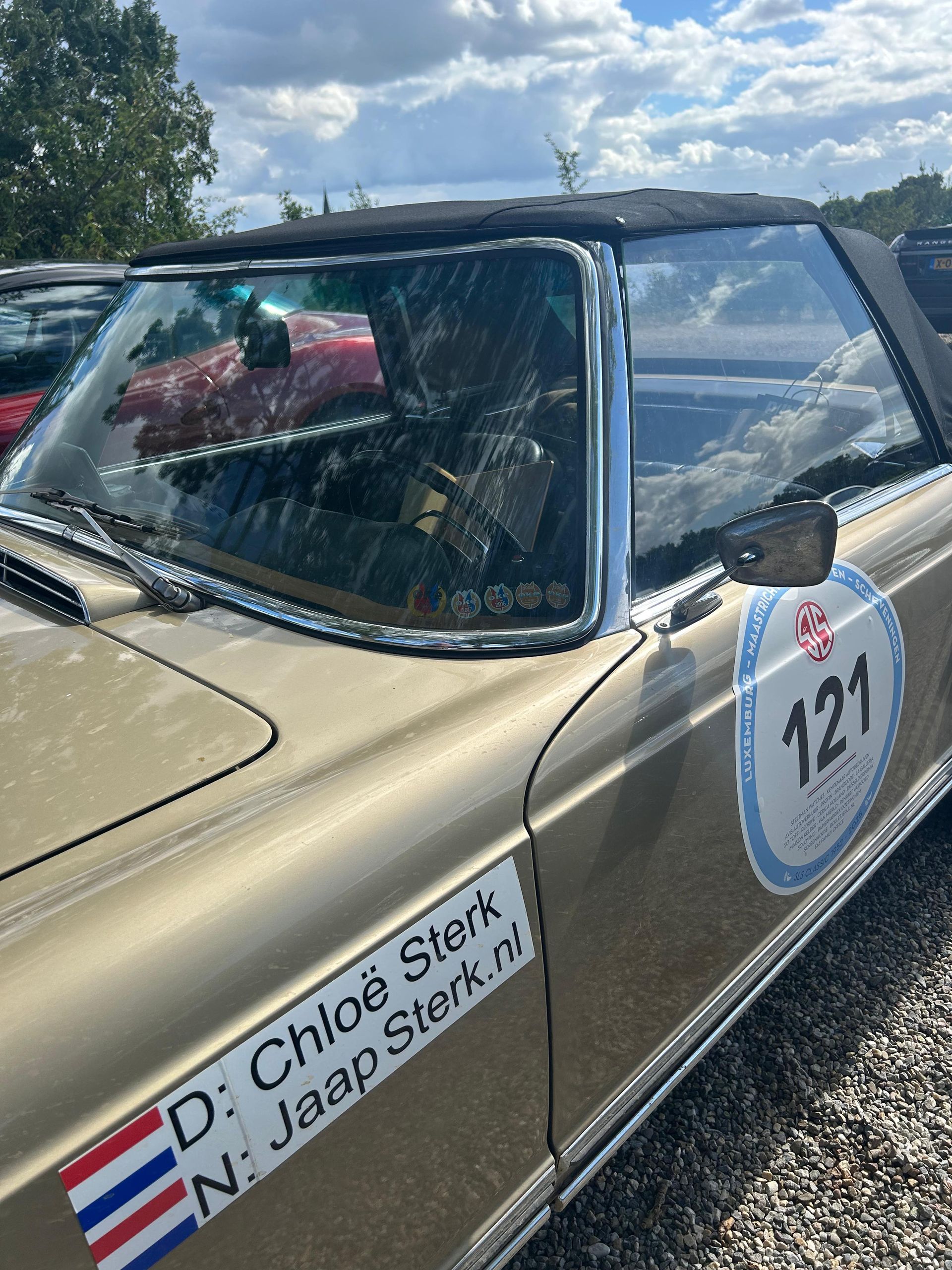Gouden cabriolet met nummer 121 sticker, twee namen op de zijkant.