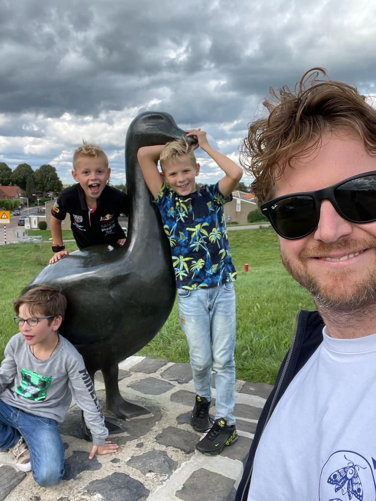 Een gezin poseert buiten op een bewolkte dag met een groot eendenbeeld.
