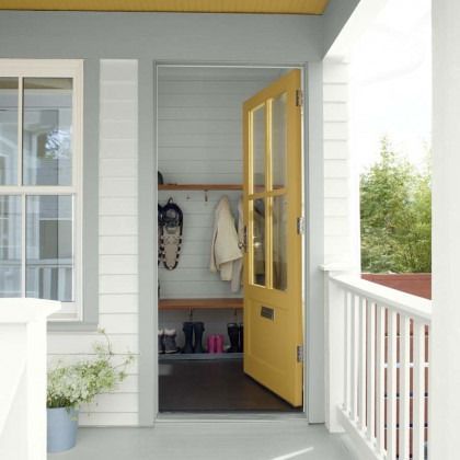 Front porch with a yellow open door, white siding, railing, and a small potted plant by the entrance.