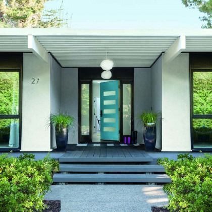 Modern house entrance with teal front door, black steps, and potted plants