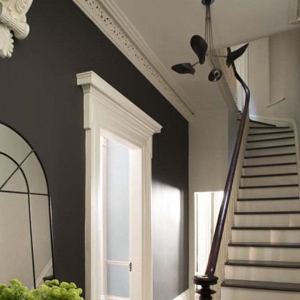 Elegant staircase with dark handrail, white trim, and black accent wall in a bright entryway.