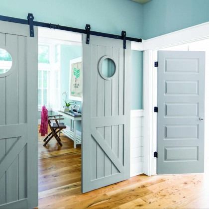 Gray barn doors open to a bright room with white trim and wood floors