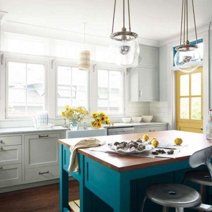 Bright white kitchen with turquoise island, yellow accents, hanging lights, and sunflowers on the counter