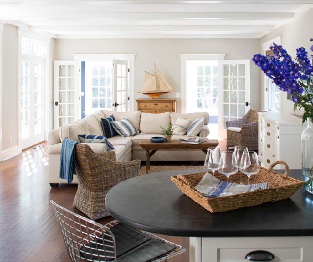 Bright airy living room with wicker sofa, striped cushions, coffee table, and blue flowers