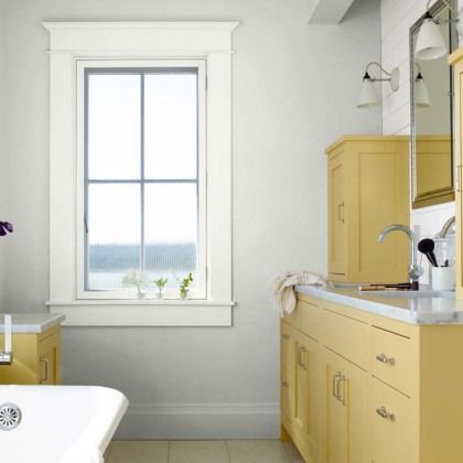Bright bathroom with yellow vanity, white tub, and window overlooking water.