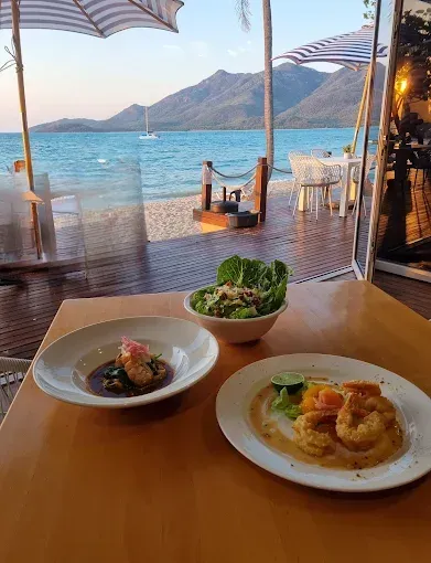 Seafood dishes on a table overlooking a beach and mountains — The Beach Bar and Restaurant at Montes in Cape Gloucester, QLD