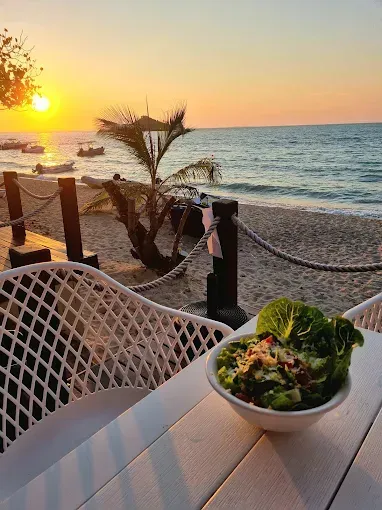 Salad bowl on a white table overlooking a beach at sunset — The Beach Bar and Restaurant at Montes in Cape Gloucester, QLD