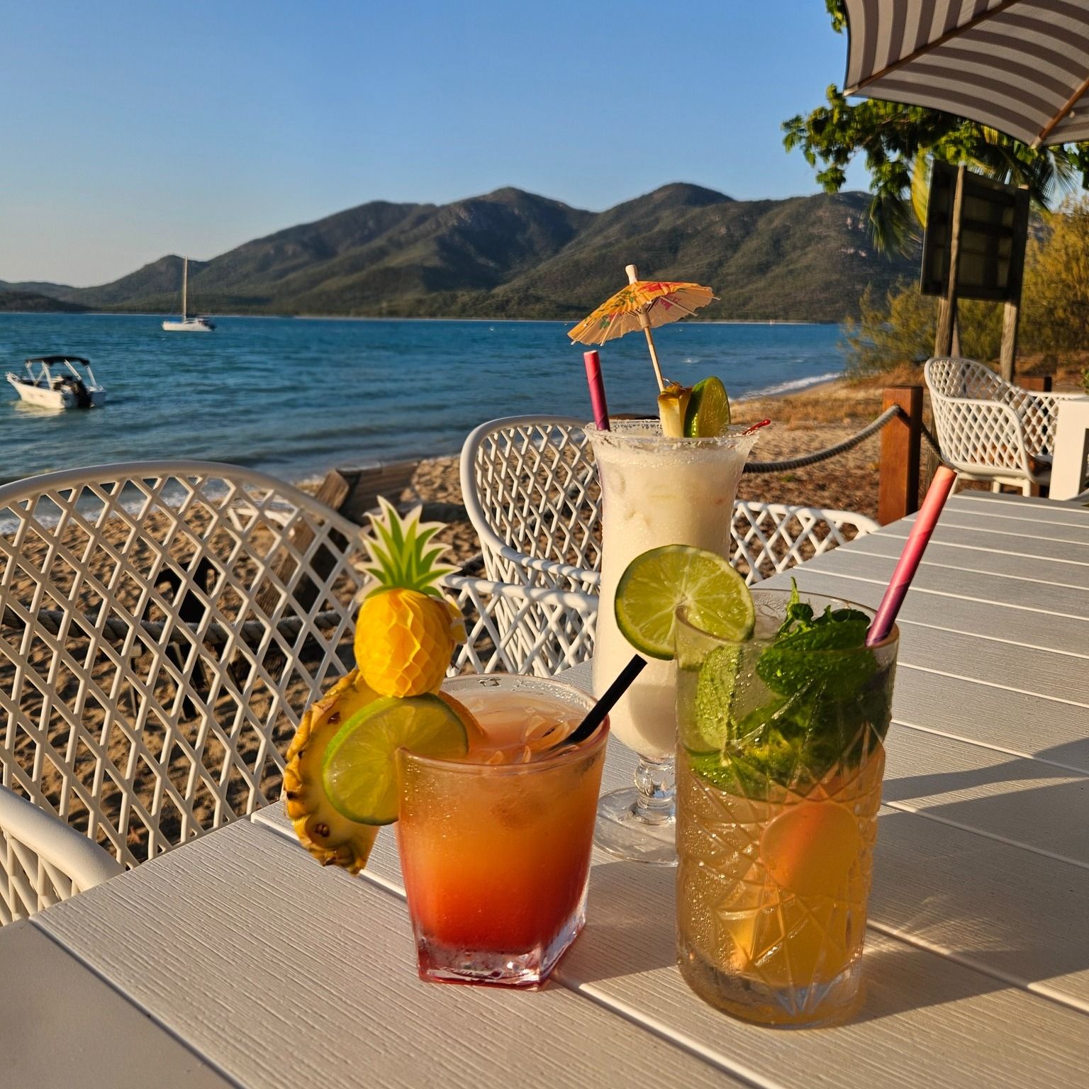 Cocktails on a table overlooking a beach and mountains — The Beach Bar and Restaurant at Montes in Cape Gloucester, QLD