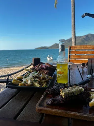 Steak and fries with a beer on a table overlooking a beach — The Beach Bar and Restaurant at Montes in Cape Gloucester, QLD