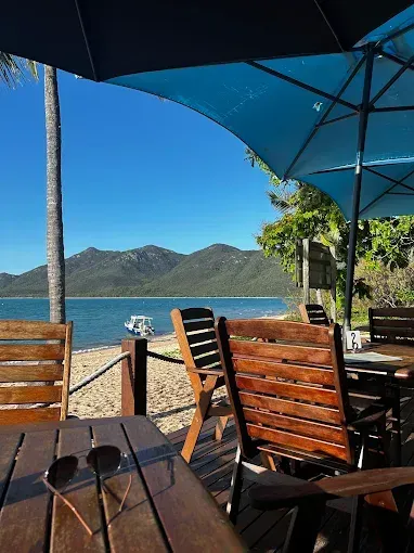 Beachside cafe with wooden tables and chairs — The Beach Bar and Restaurant at Montes in Cape Gloucester, QLD