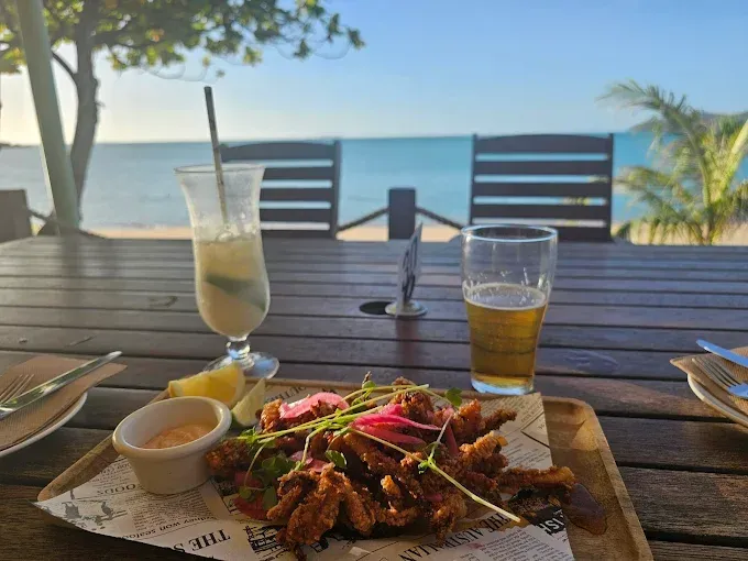 Food platter, cocktail, and beer on a wooden table — The Beach Bar and Restaurant at Montes in Cape Gloucester, QLD
