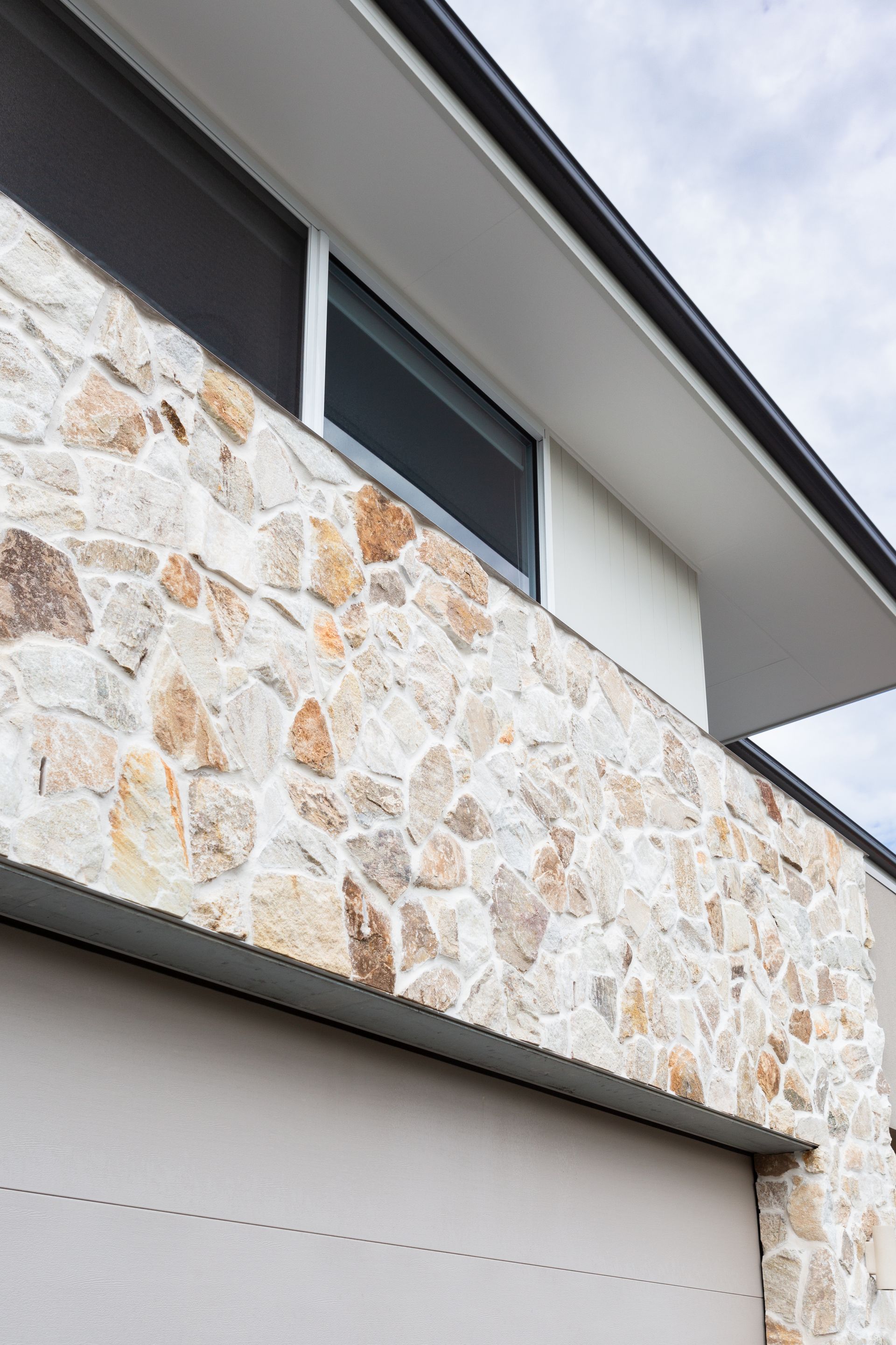 Stone facade of a building with a window and a garage door underneath.