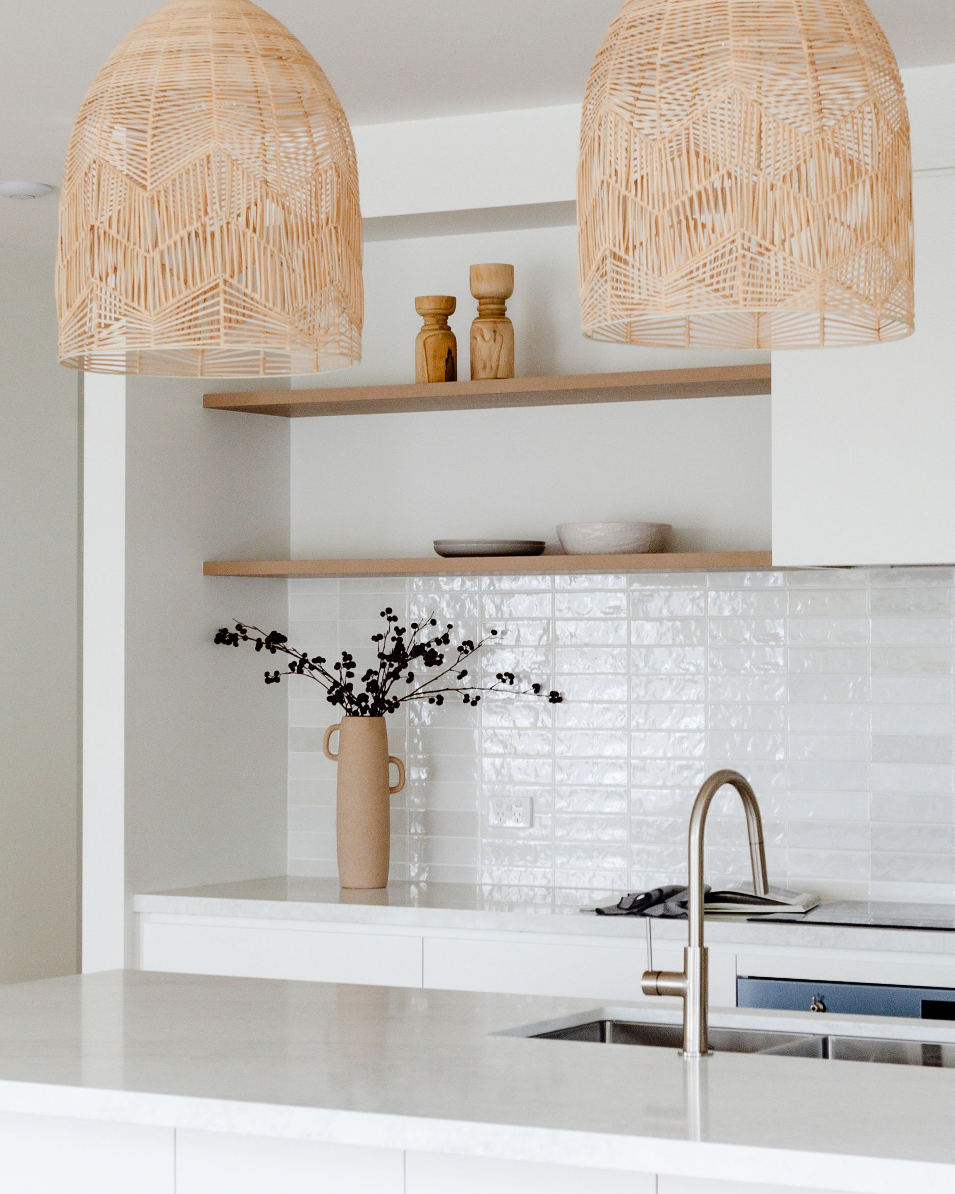 Kitchen with woven pendant lights, open shelving, and white tile backsplash.