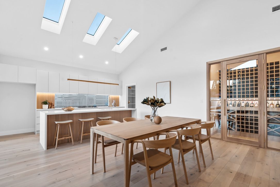 Bright kitchen/dining area with wood floors, a long table, and a built-in wine rack.