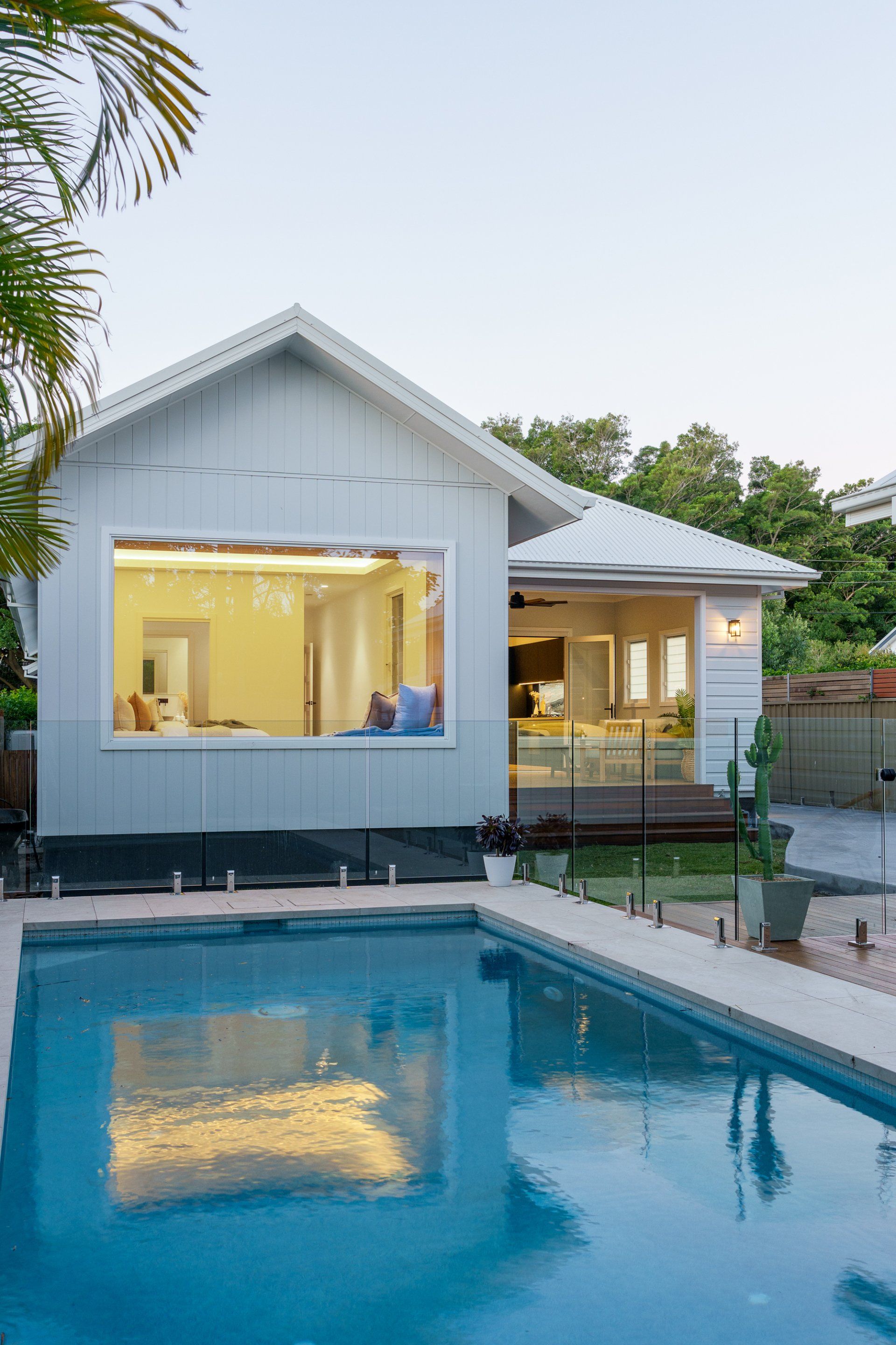 Light blue house with open windows overlooking a pool.