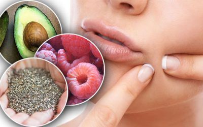A woman is touching her face with avocado , raspberries , and chia seeds.