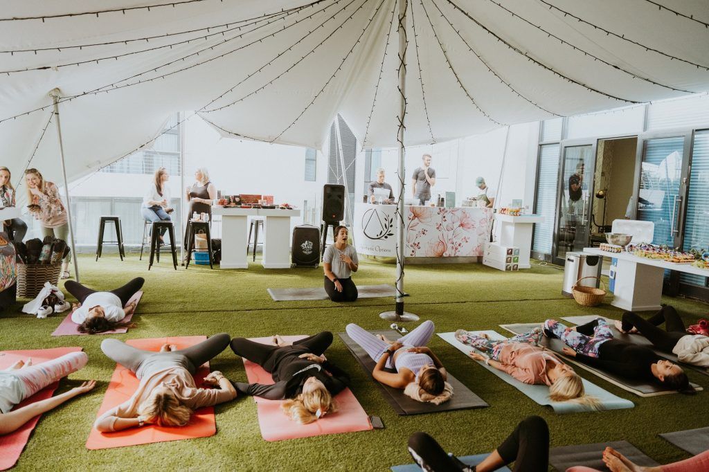 A group of people are laying on yoga mats under a tent.