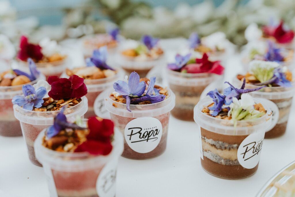 A bunch of small cups filled with desserts and flowers on a table.