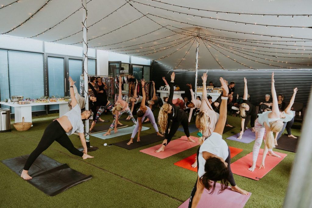 A group of people are doing yoga in a tent.