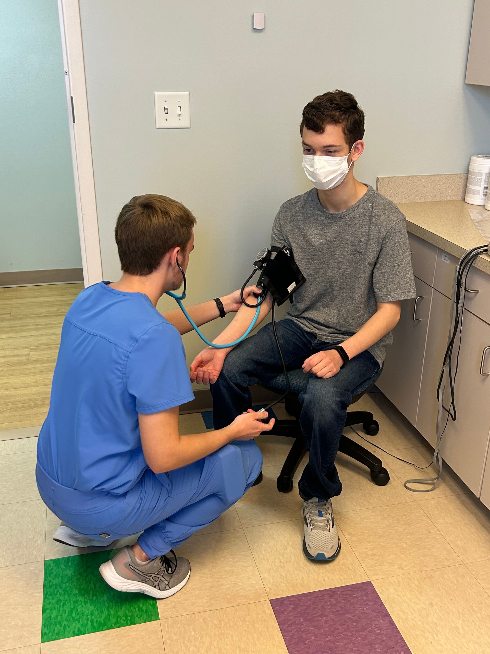 Pediatrician taking blood pressure of a teenage boy