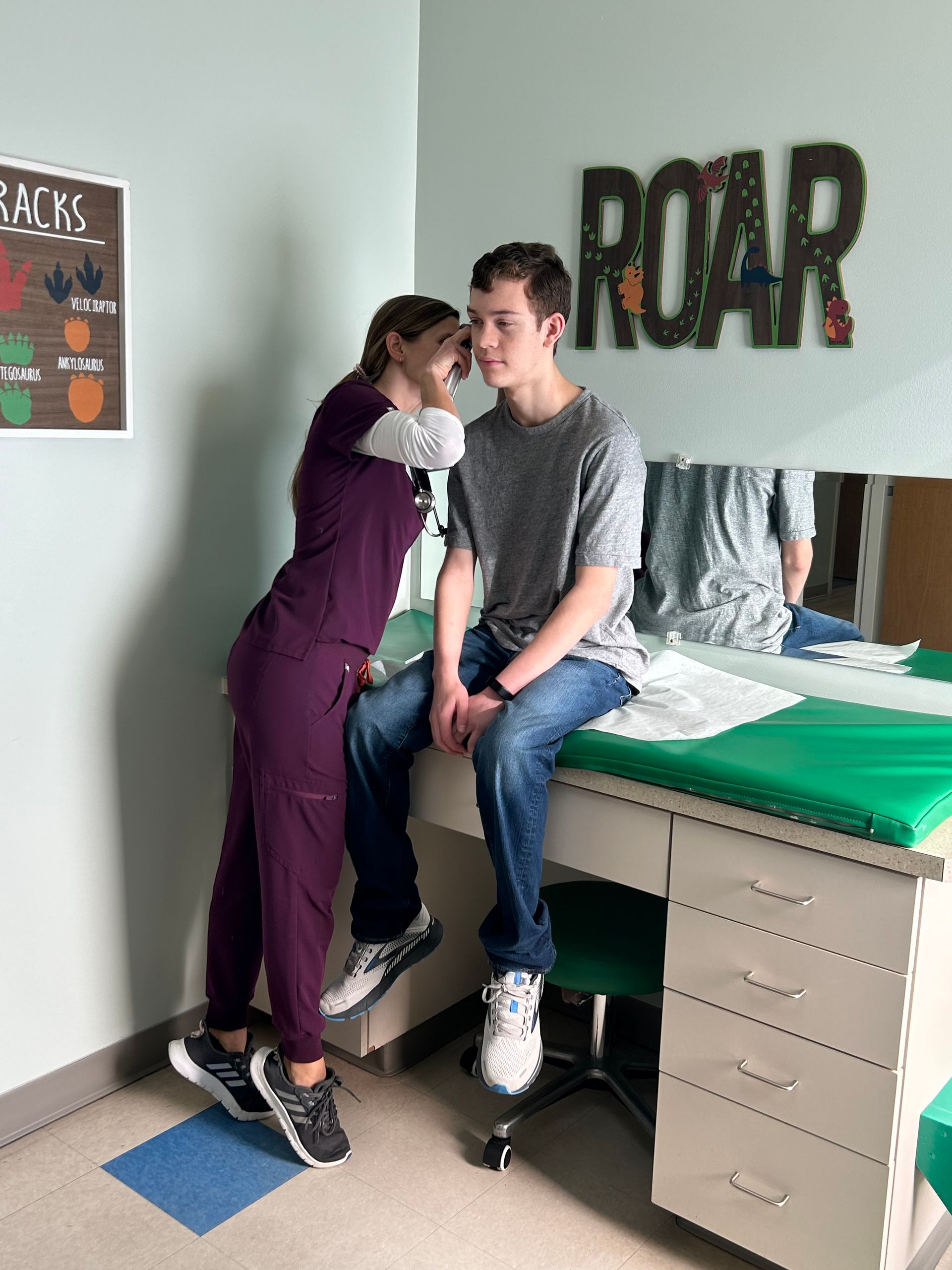 Pediatrician looking in the ear of a teenage boy