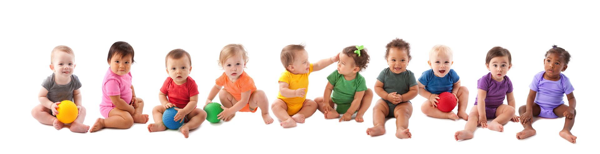 A group of babies are sitting in a row holding balls.