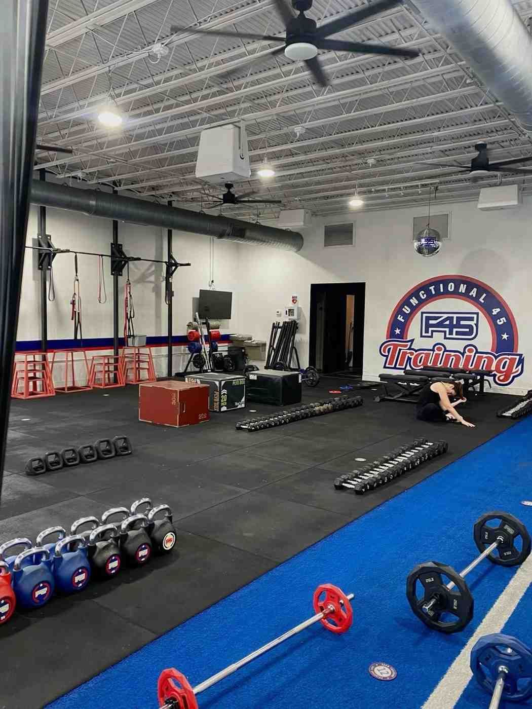 Gym interior with exercise equipment and a person training. Blue, red, and black.