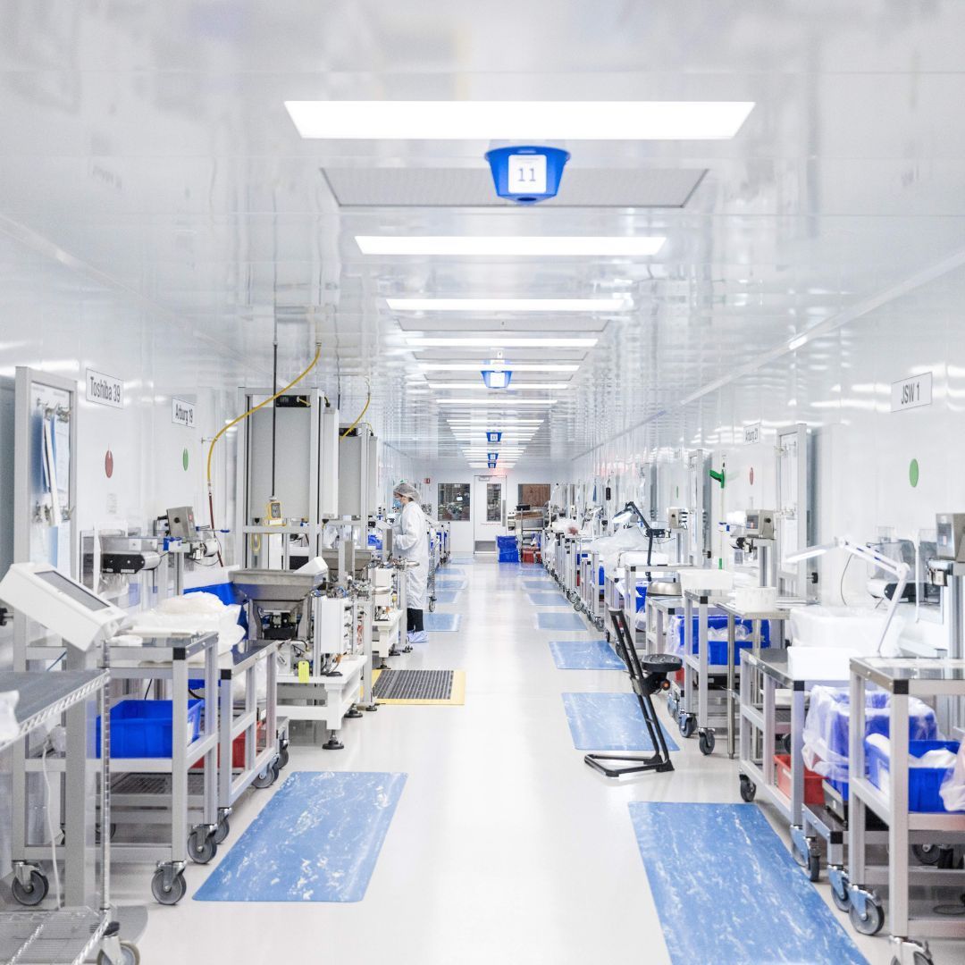 Clean white medical facility hallway with equipment and workers.