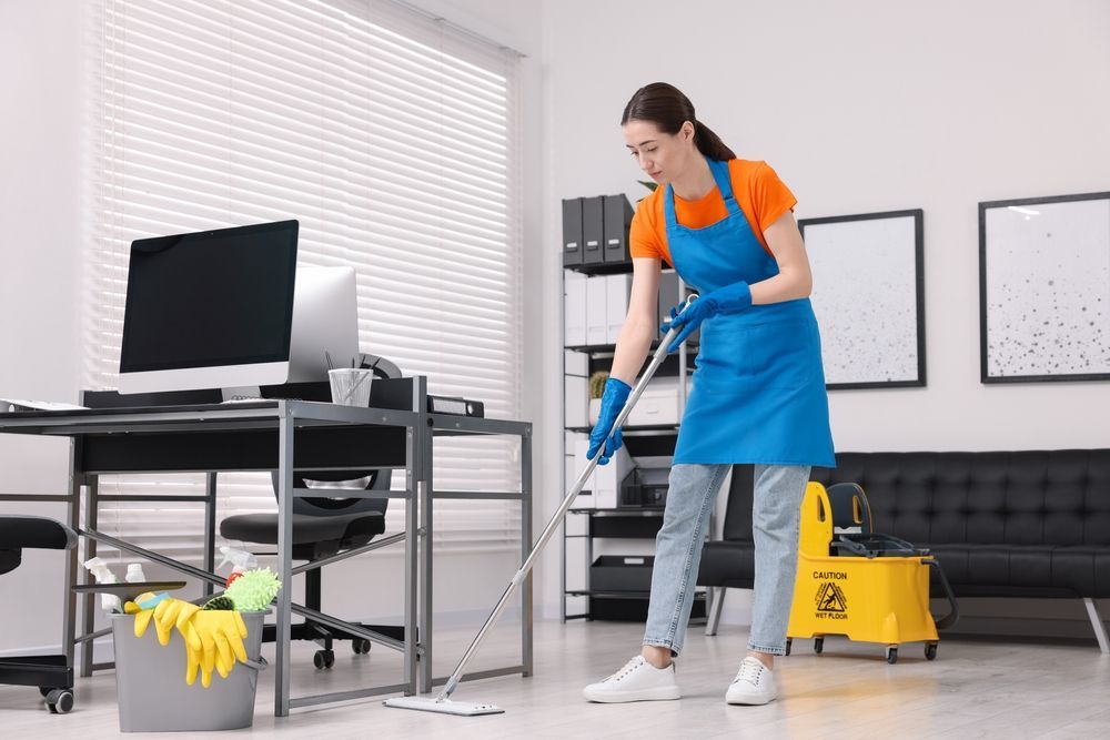 Office floor cleaning with mop, bucket, and desk background
