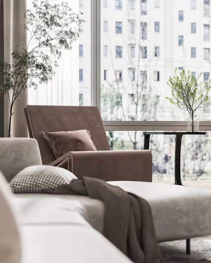 Cozy modern living room with neutral colors, large windows, and outdoor views; a chaise lounge and side table.