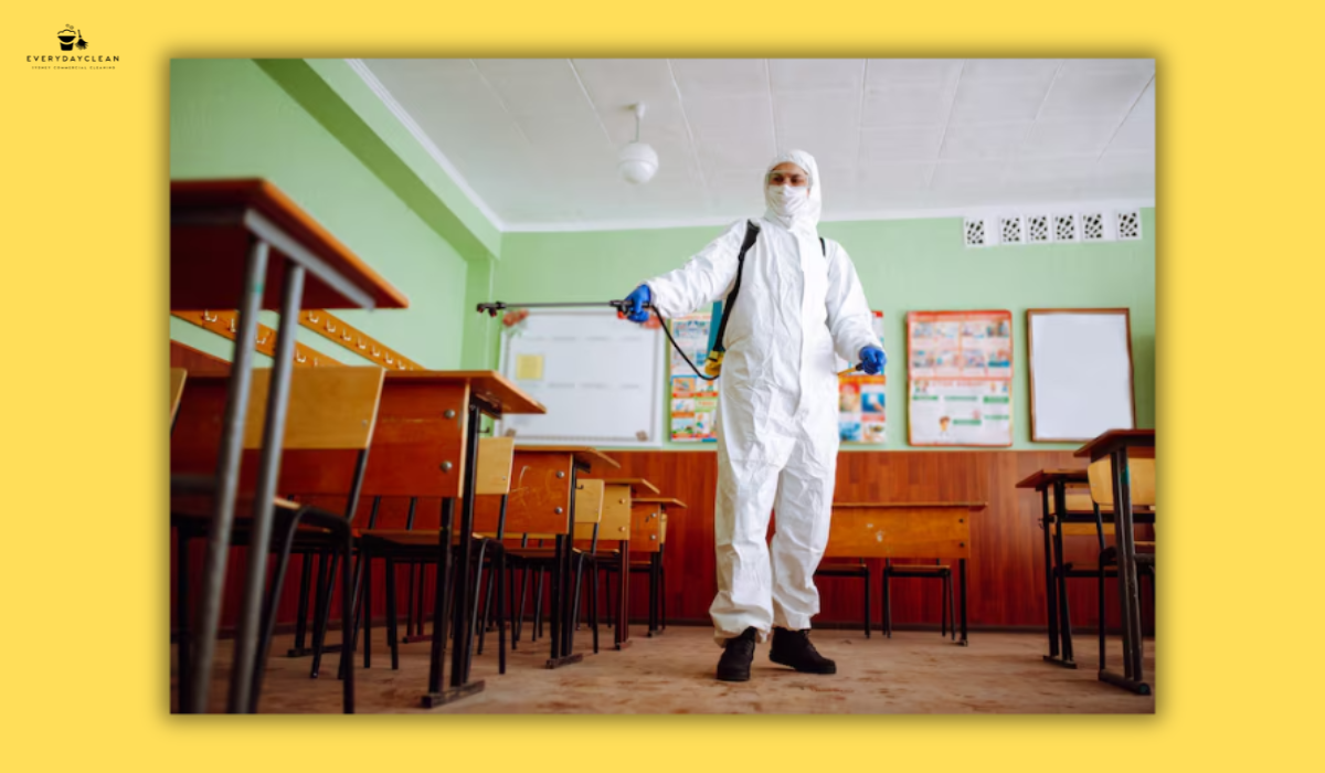 Person in protective suit sprays disinfectant in a classroom.