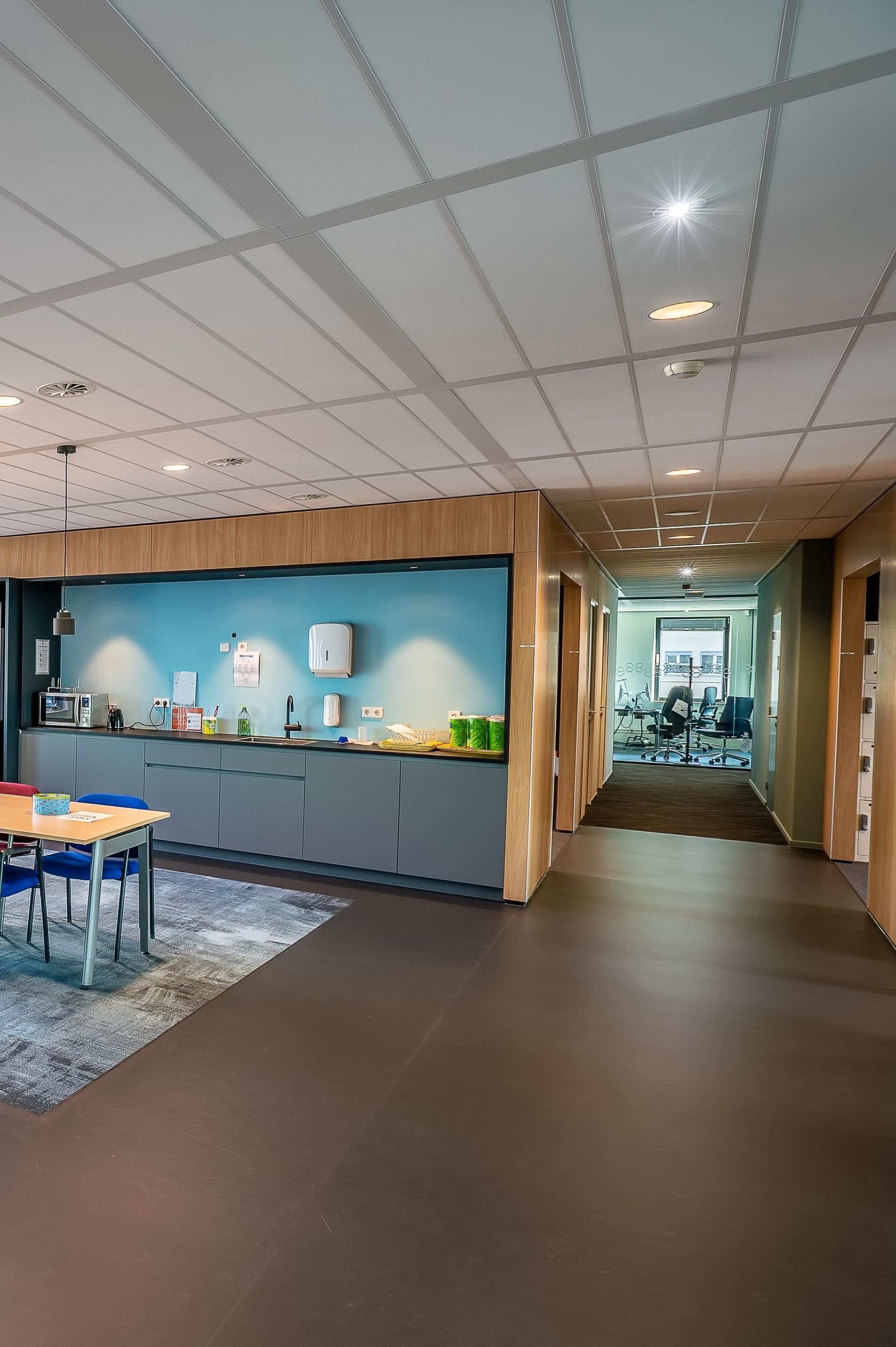 Hallway with kitchenette, blue accent wall, and doors leading to other rooms.