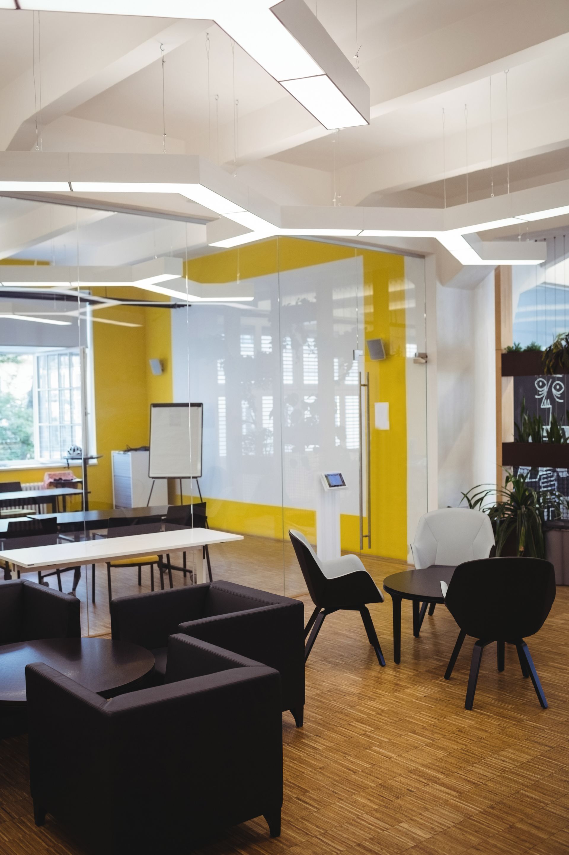 Modern office interior with yellow accents, featuring lounge area and collaborative workspace.